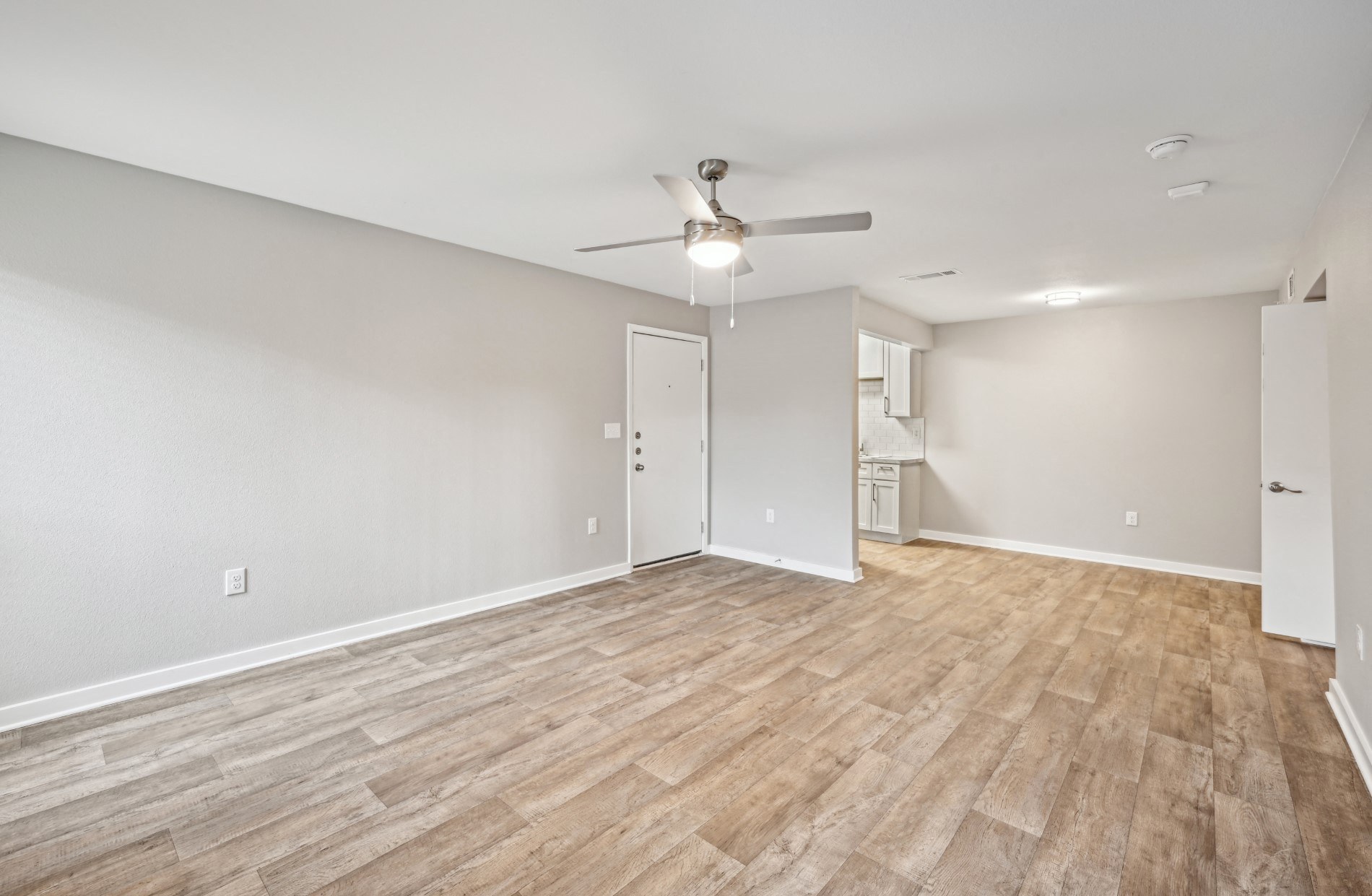 the living room of an empty house with a ceiling fan